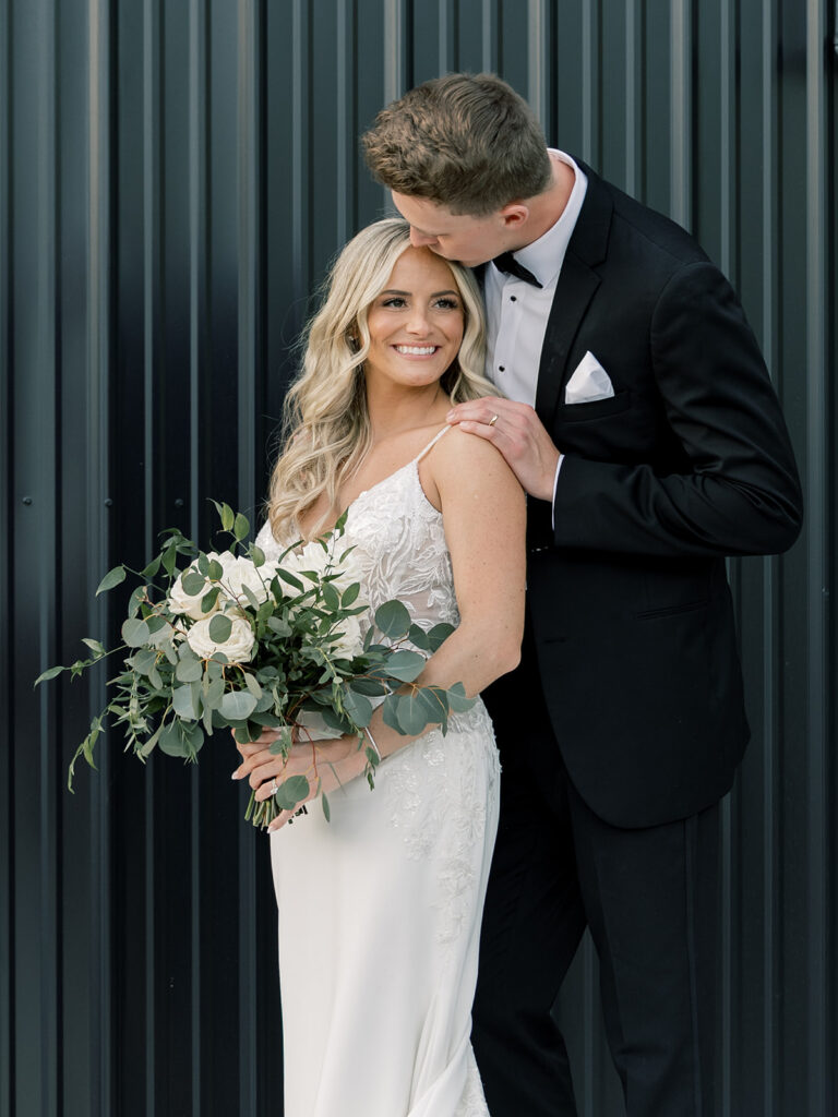 Bride and groom portrait against black siding at Venue Bella Giornata