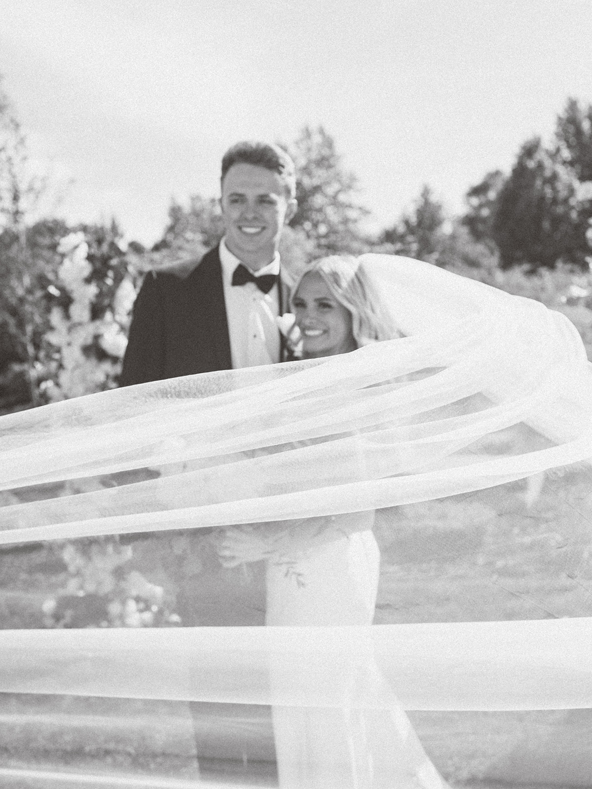 Black and white portrait of bride and groom with flowing veil at Bella Giornata
