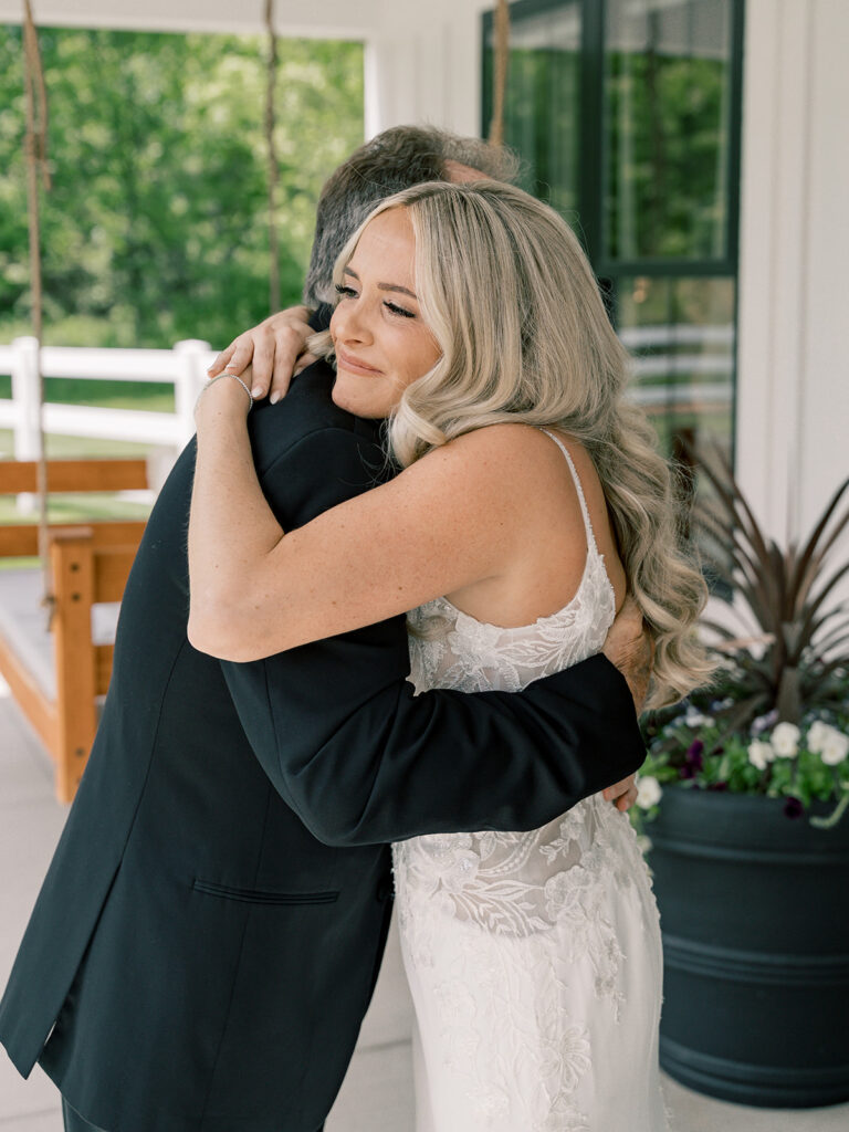 Father and daughter first look hug on the porch at Bella Giornata wedding venue