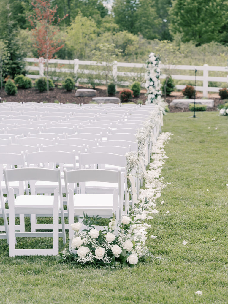 Outdoor ceremony setup with white chairs and white floral pillars at Bella Giornata