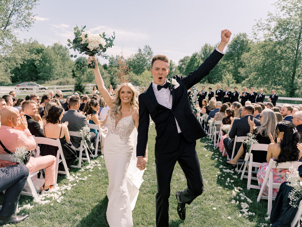 Newlyweds celebrate walking back up the aisle at Bella Giornata in Byron Center