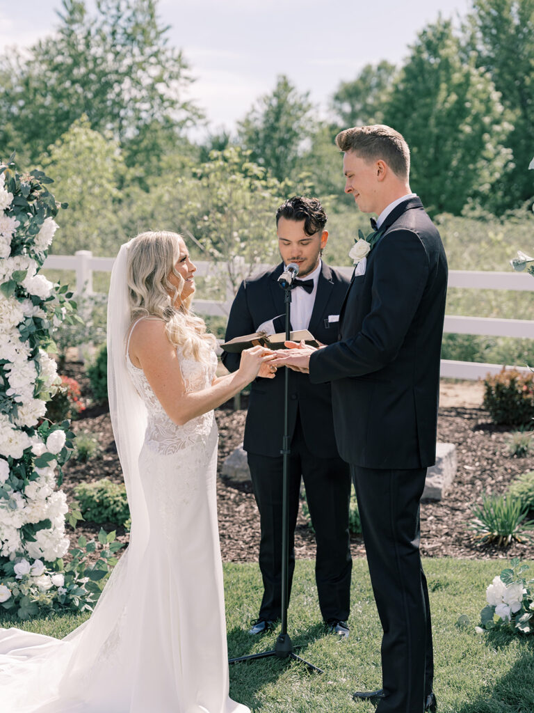 Bride and groom exchanging vows between white floral pillars at Bella Giornata